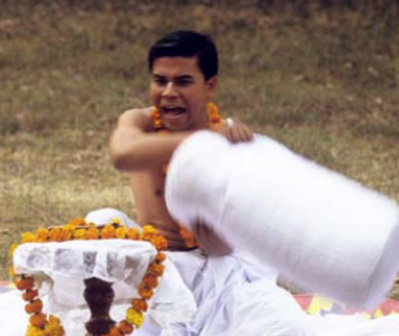 A photo of a wari leeba performance by Dr. Singh Mayanglambam.  He is dressed in white pants and swinging a white pillow