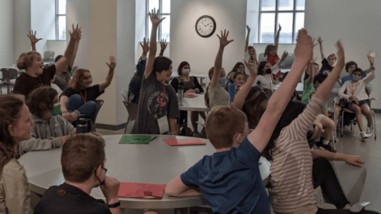 Kids in a classroom raising their hands