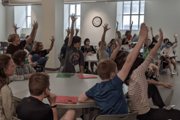 Kids in a classroom raising their hands